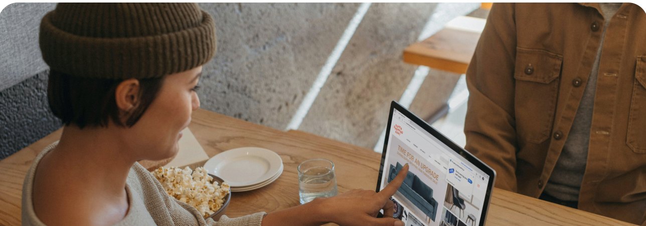 A woman browsing a task board on her laptop at a cafe table